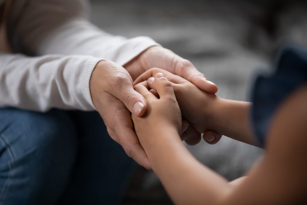 An adult holding hands with a child.
